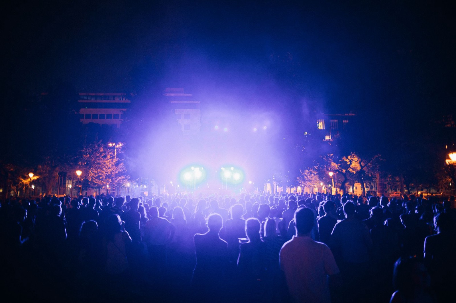 Scène de concert en plein air éclairée la nuit devant la foule d'un festival